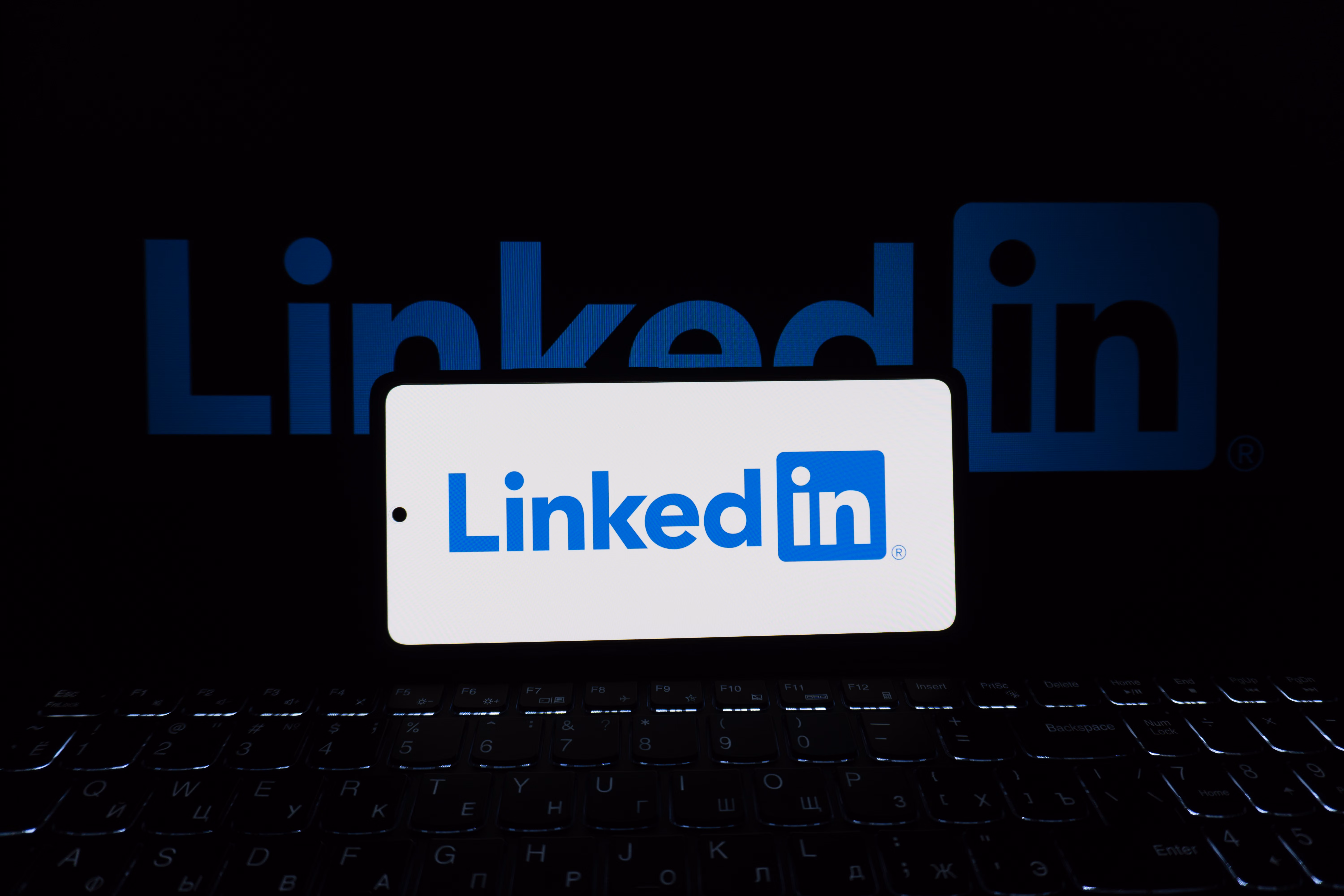 Smartphone affichant LinkedIn à côté d’un ordinateur portable pour illustrer une prospection professionnelle en ligne