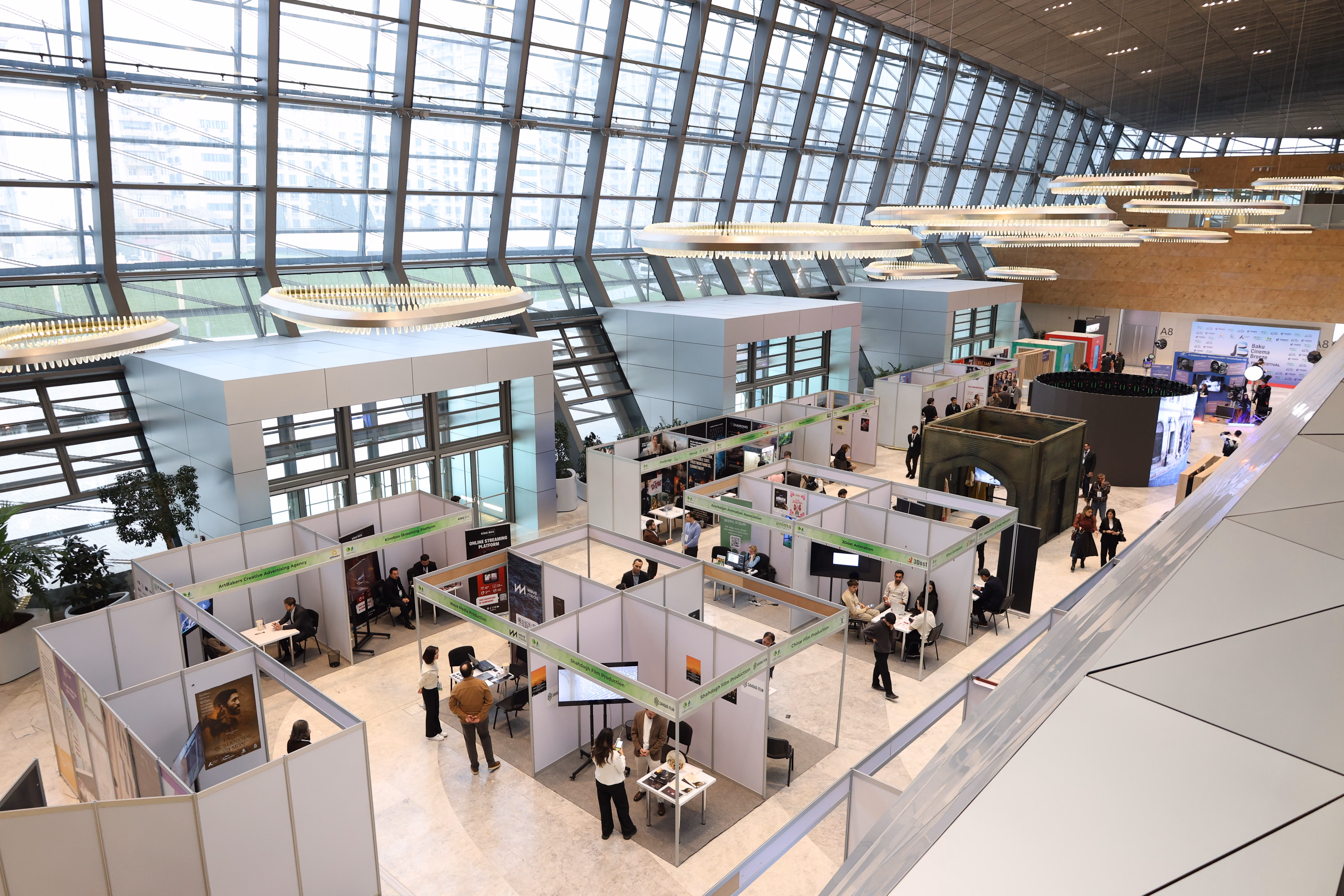 Salon professionnel avec plusieurs stands et participants échangeant autour d’espaces partenaires