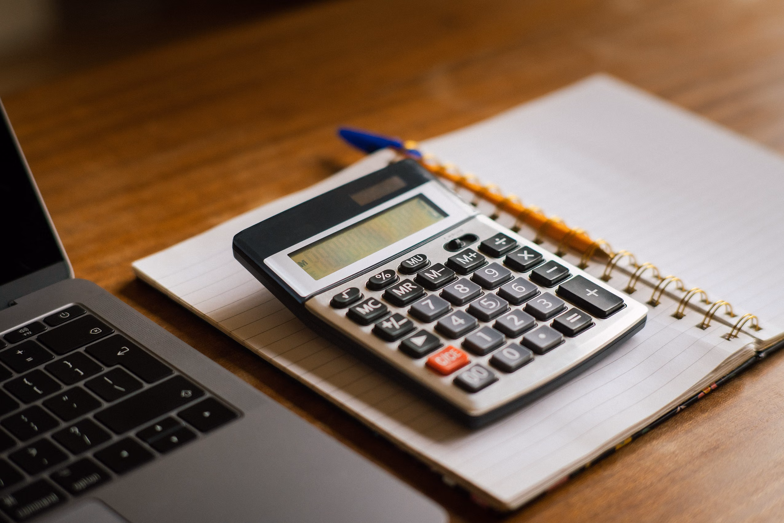 Ordinateur portable et calculatrice sur un bureau pour préparer un budget associatif
